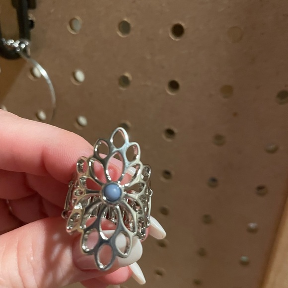 Long openwork silver ring with tiny blue center.